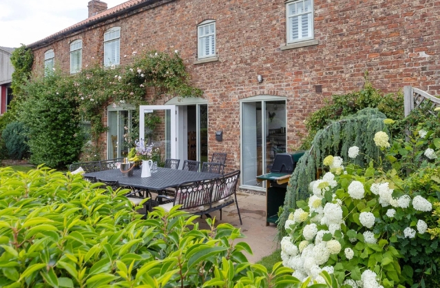 Charming garden and outdoor dining area at The Old Grain Store, a cosy Yorkshire hen party house.