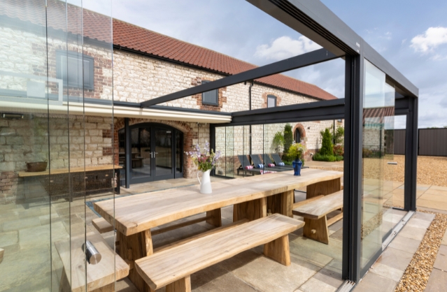 Modern barn conversion with glass-enclosed outdoor dining area at Derwent Barn in Yorkshire