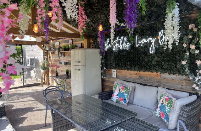 Outdoor covered seating area with floral décor and neon sign at Streona House, a stylish hen party property near York.