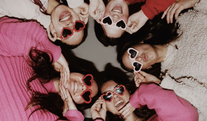 Friends celebrating Galentine’s Day, lying together in a circle with heart sunglasses and relaxed vibes